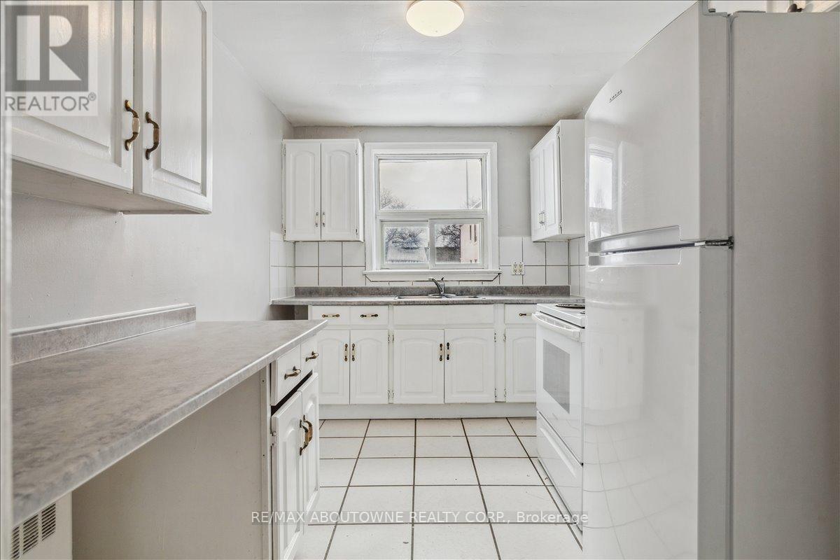 A white kitchen with a refrigerator on the right.