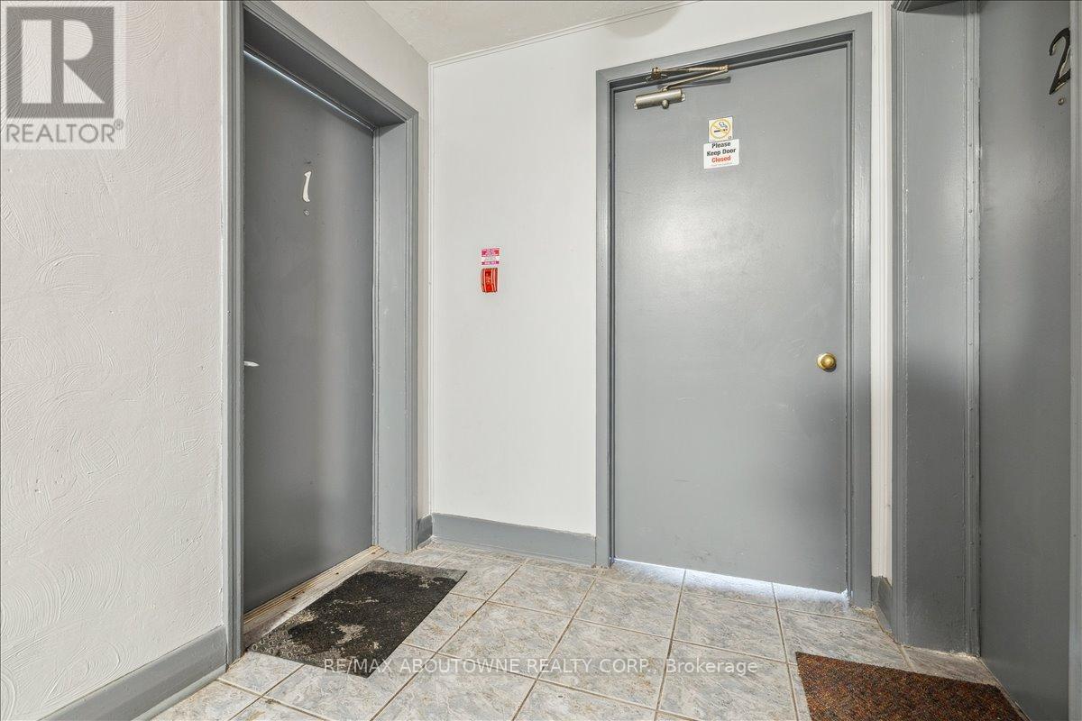 A hallway with two doors, one of which is closed and has a fire extinguisher on the wall.