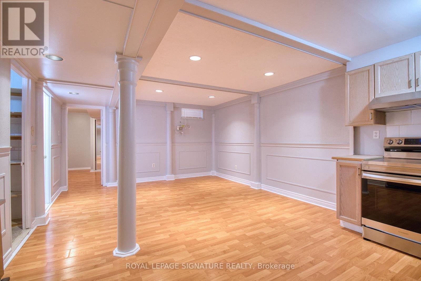 A spacious kitchen with wooden floors and white walls.