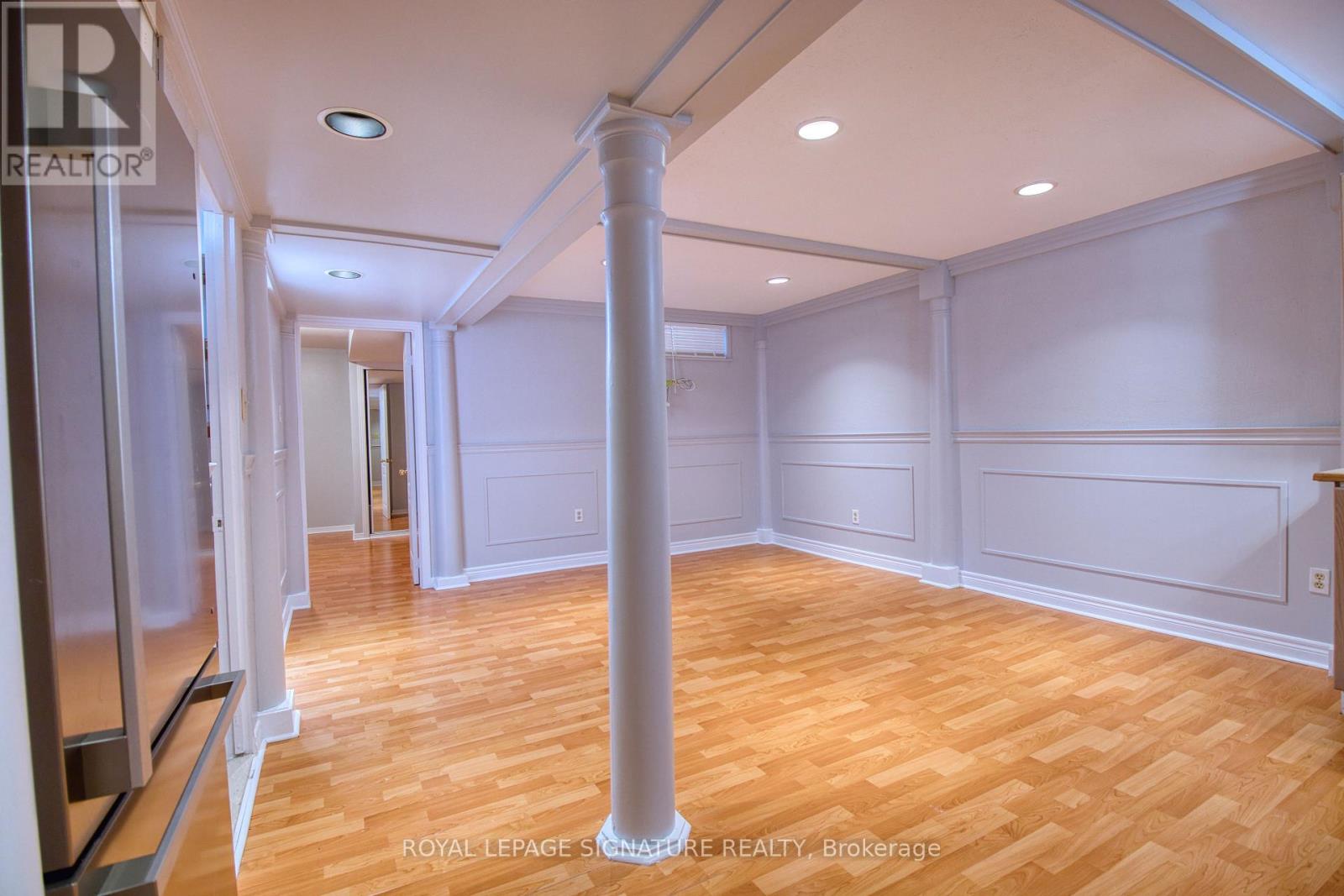 A spacious room with wooden flooring and white walls.