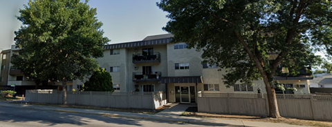 A large apartment building with a tree in front of it.
