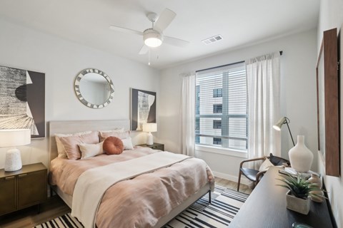 A bedroom with a large bed and a ceiling fan.