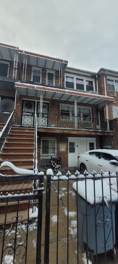 A white car is parked in front of a brick house.