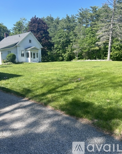 A white house with a green lawn in front of it.