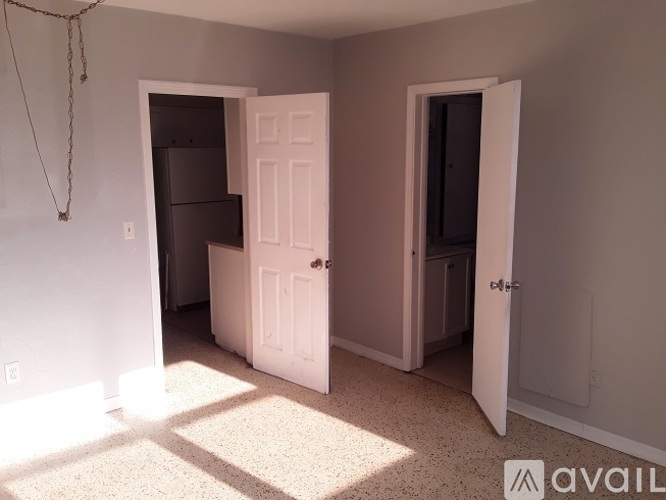 A room with two doors, one open, and a chain hanging from the ceiling.