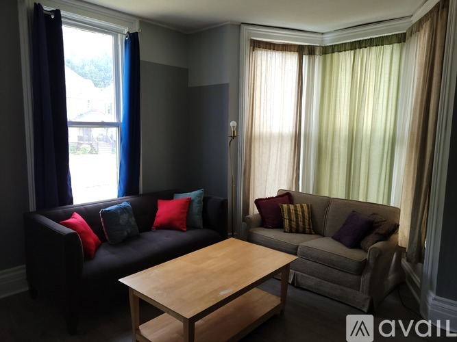A living room with a black couch, a wooden coffee table, and a grey couch with pillows.
