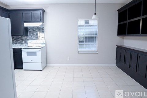 A kitchen with black cabinets and a white fridge.