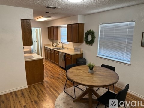 A kitchen with a table and chairs in the foreground and a wreath on the wall.