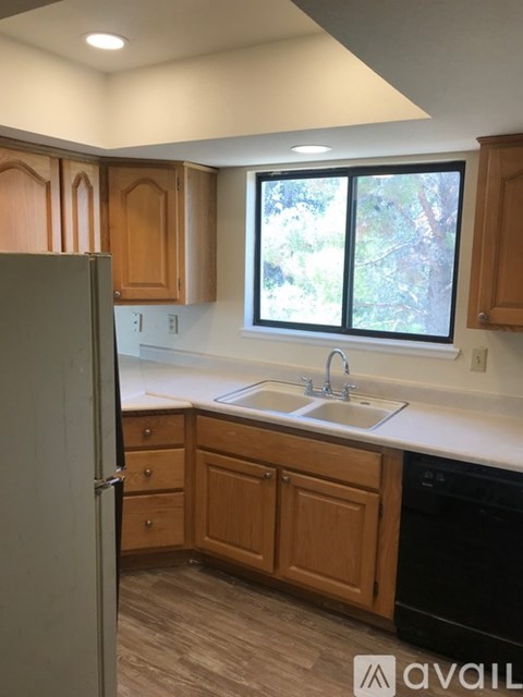 A kitchen with wooden cabinets and a black dishwasher.