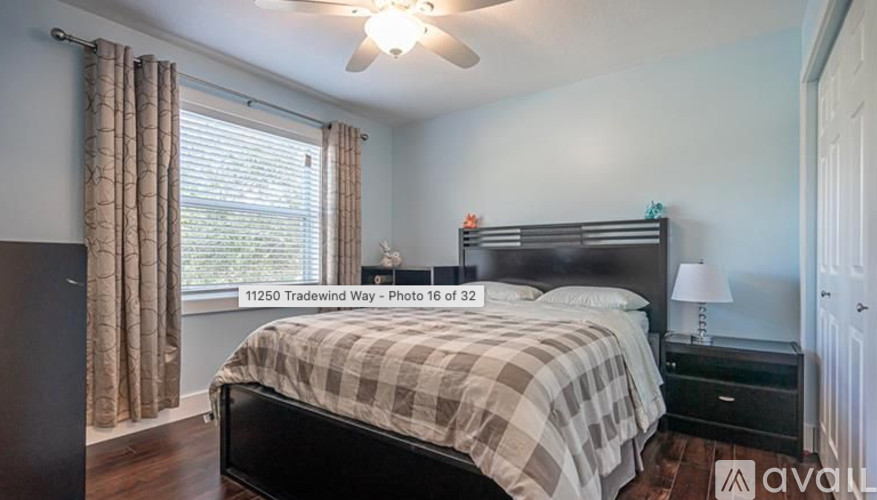 A bedroom with a bed, nightstand, and window with curtains.