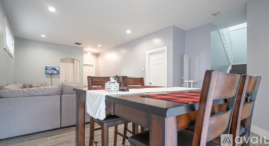 A dining room with a table set for two and a couch in the background.