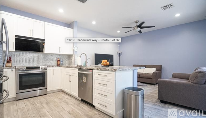 A modern kitchen with a stainless steel oven and a grey couch.