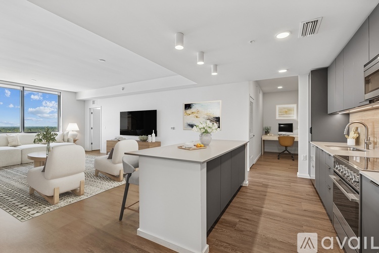 A modern kitchen with a large island and a living area with a couch and chairs.