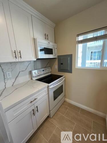 A kitchen with white cabinets and a marble countertop.