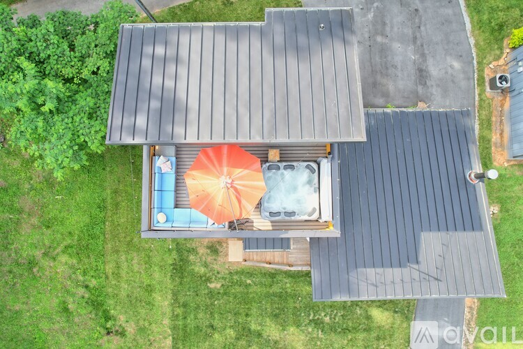 A hot tub is surrounded by a wooden deck and a grey roof.