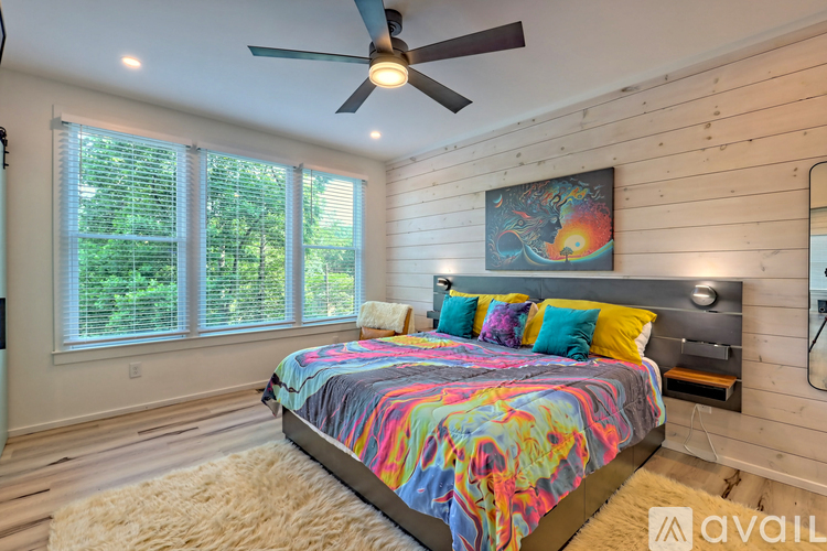 A bedroom with a bed, a ceiling fan, and a painting on the wall.