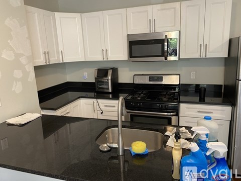 A kitchen with white cabinets and black countertops.