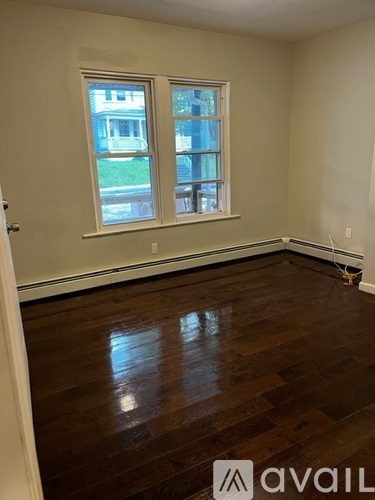 A room with wooden floors and two windows.