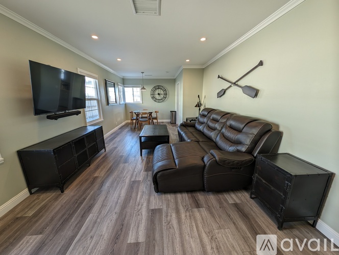 A living room with a black leather couch and a television.