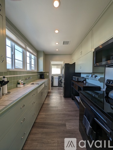 A kitchen with black appliances and green cabinets.
