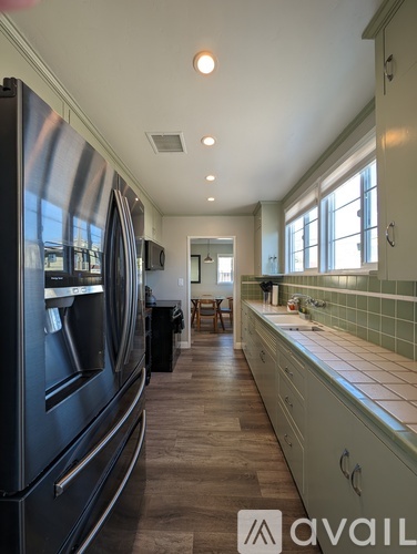 A modern kitchen with a black refrigerator and wooden floors.