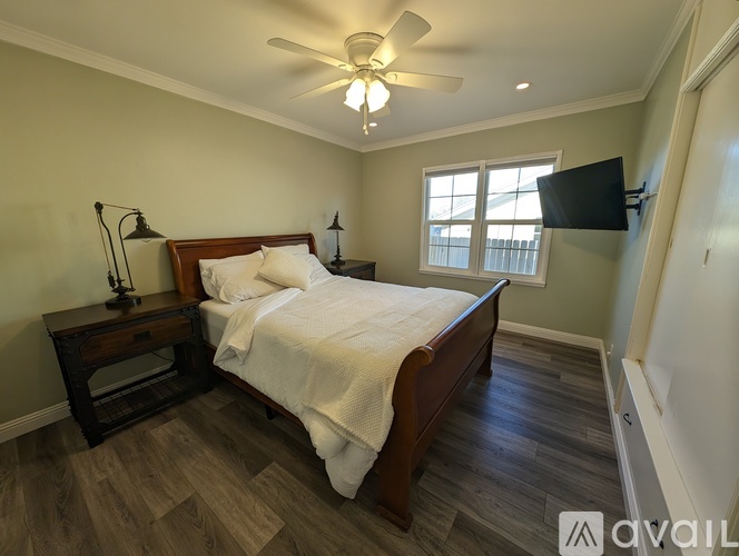 A bedroom with a bed, nightstand, and a ceiling fan.