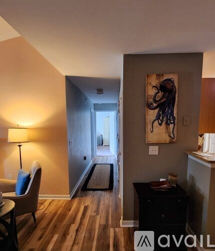 A living room with a chair, a table, and a painting on the wall.