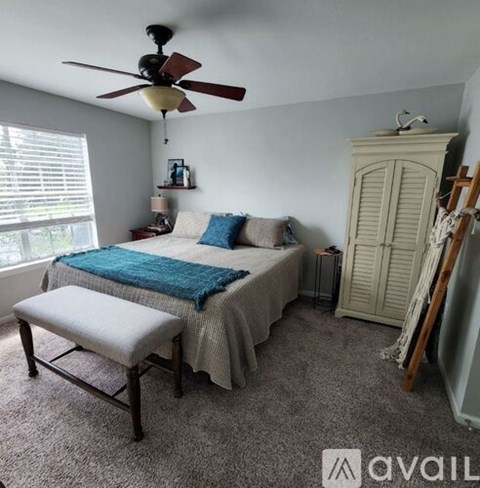 A bedroom with a bed, a chair, and a fan.