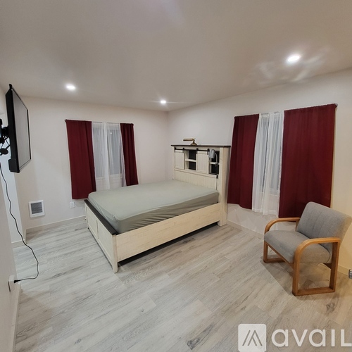A bedroom with a bed, chair, and a television.