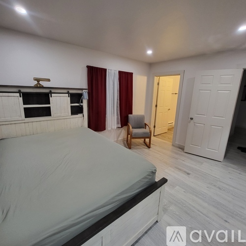 A bedroom with a bed, chair, and two doors.