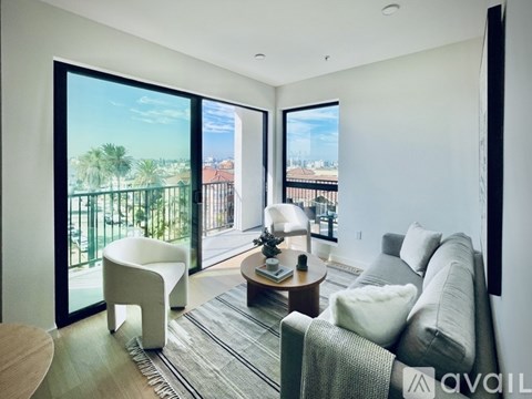 A living room with a couch, chair, and coffee table with a view of the outside.