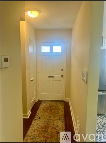 A hallway with a rug and a white door.