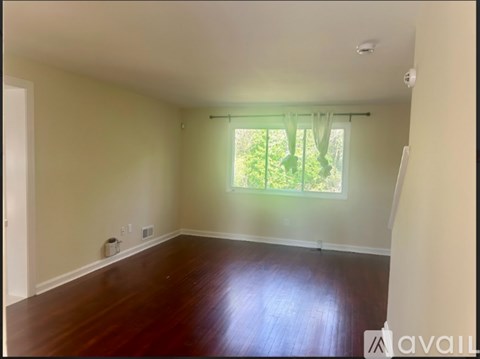 A room with wooden floors and a window with green curtains.
