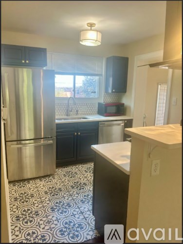 A kitchen with a tile floor and a refrigerator.