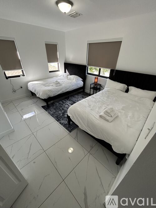 A bedroom with two beds and a marble floor.