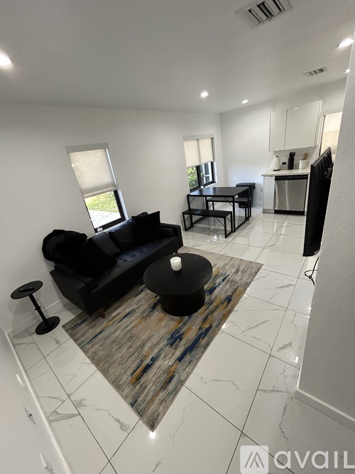 A living room with a black couch and a rug.