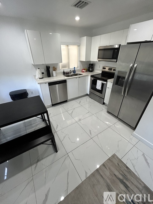 A kitchen with a black table and stainless steel appliances.