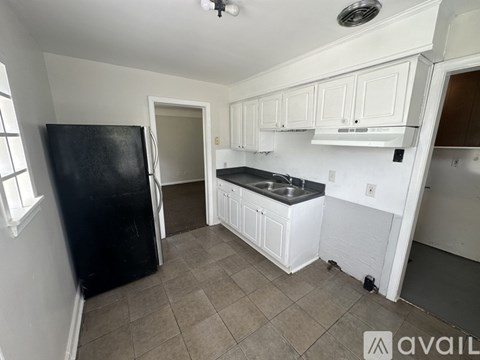 A kitchen with white cabinets and a black refrigerator.