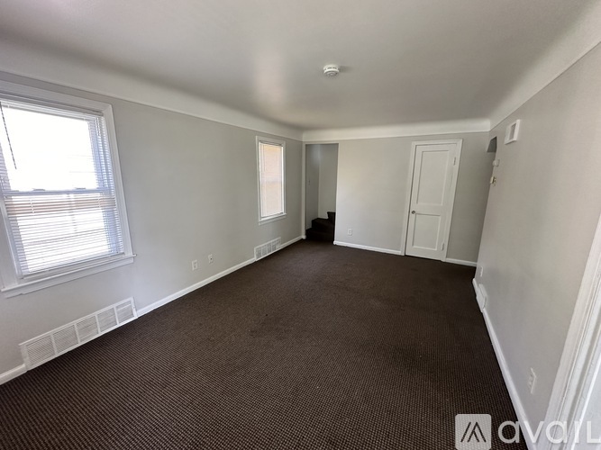 A spacious room with carpeted floor and white walls.