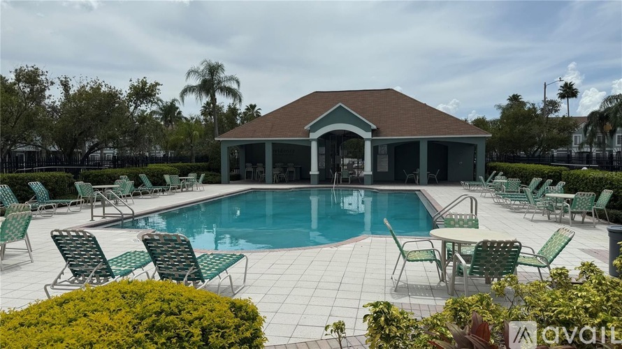 A pool area with chairs and a building in the background.