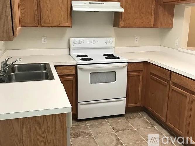 A white stove and sink in a kitchen with wooden cabinets.