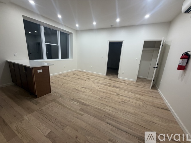 A room with wooden flooring and a fire extinguisher on the wall.