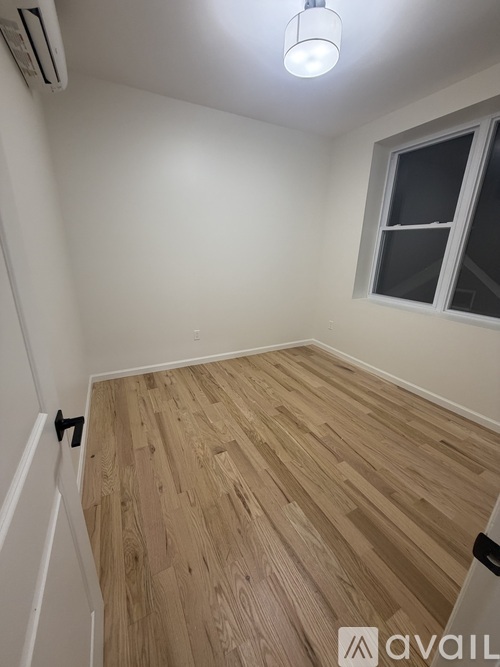 A room with wooden flooring and a window.