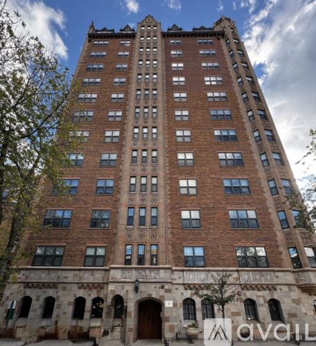 A tall red brick building with many windows and a stone base.