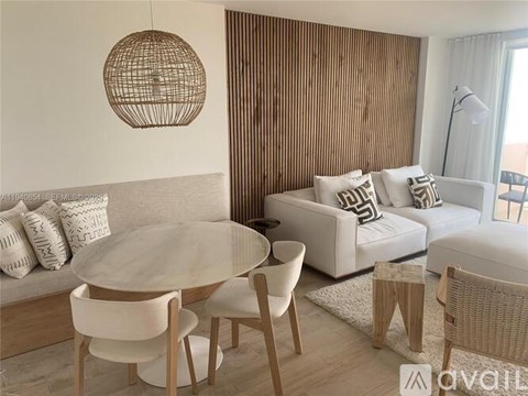 A modern living room with a glass table and white chairs.