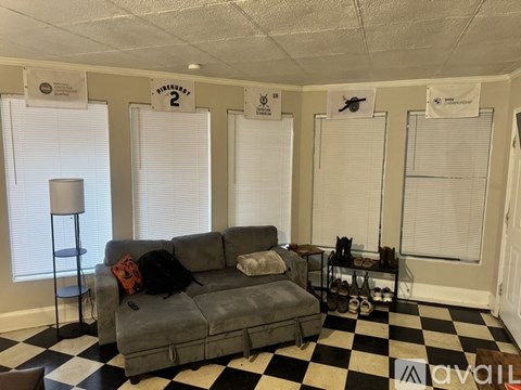 A living room with a grey couch and a black and white checkered floor.