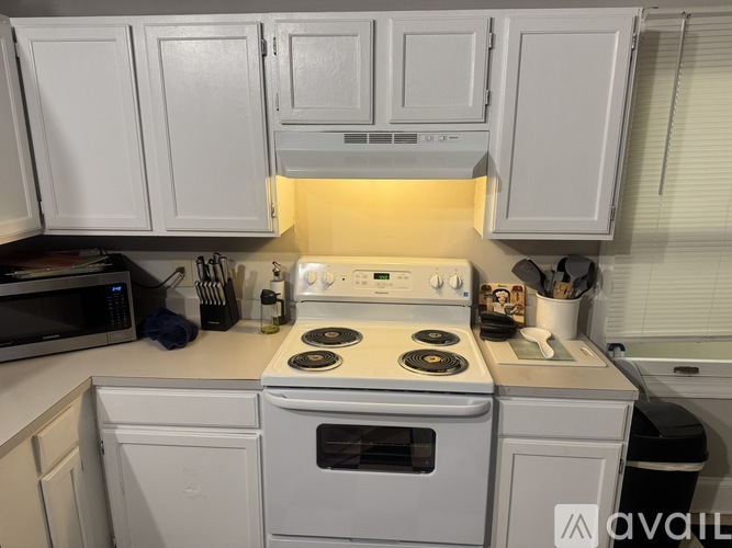 A white kitchen with a stove top oven and microwave.