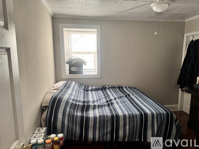 A bedroom with a bed, a window, and a coat rack.