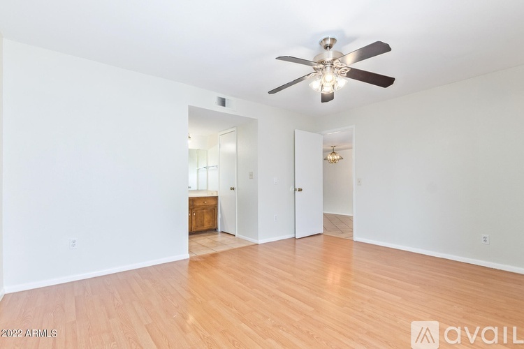 A spacious room with a ceiling fan and wooden flooring.