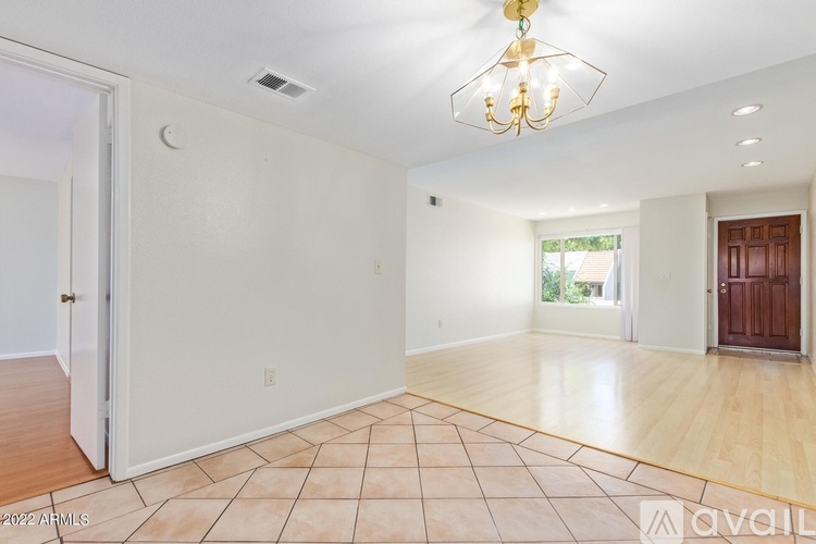 A large empty room with a chandelier and tiled flooring.